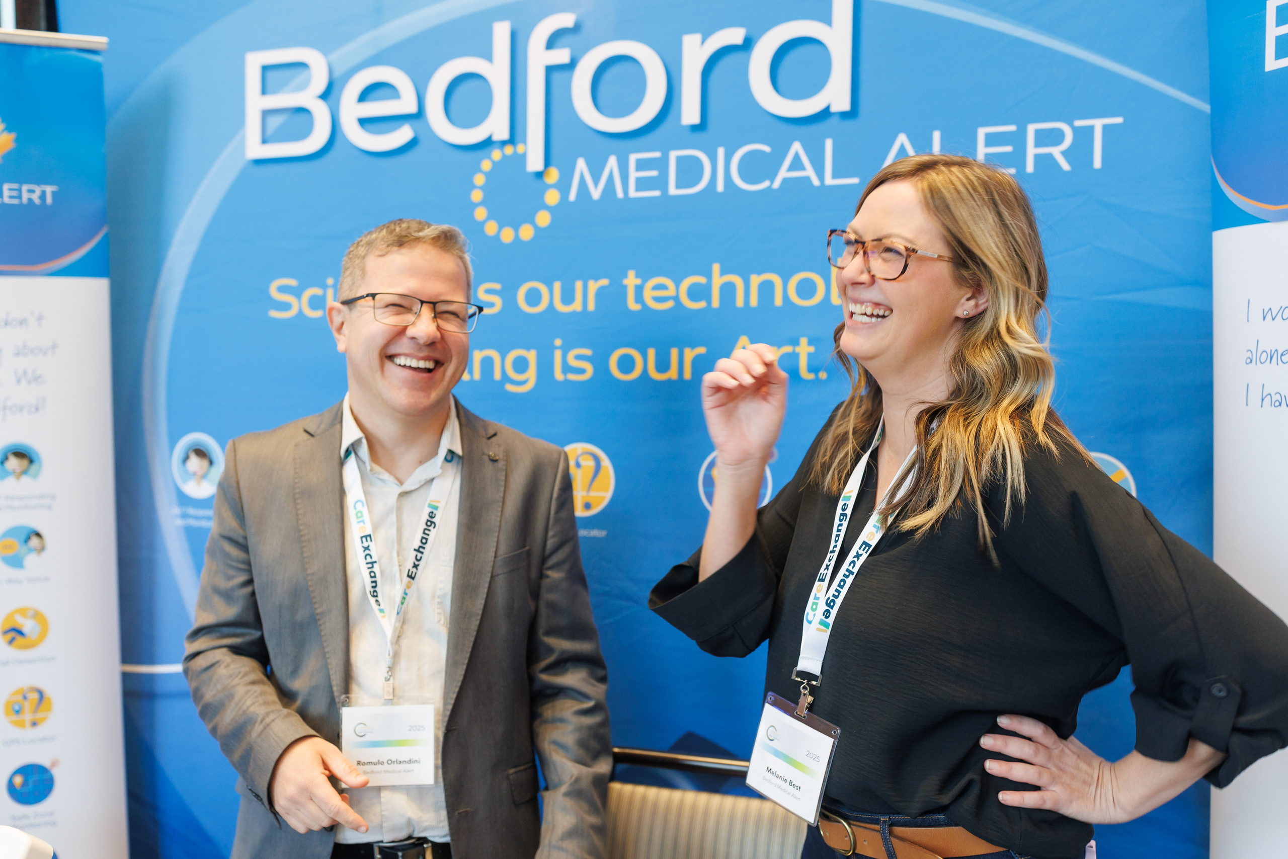 Two Bedford Medical Alert team members standing at a conference booth showcasing nurse call systems for senior care in Ontario.